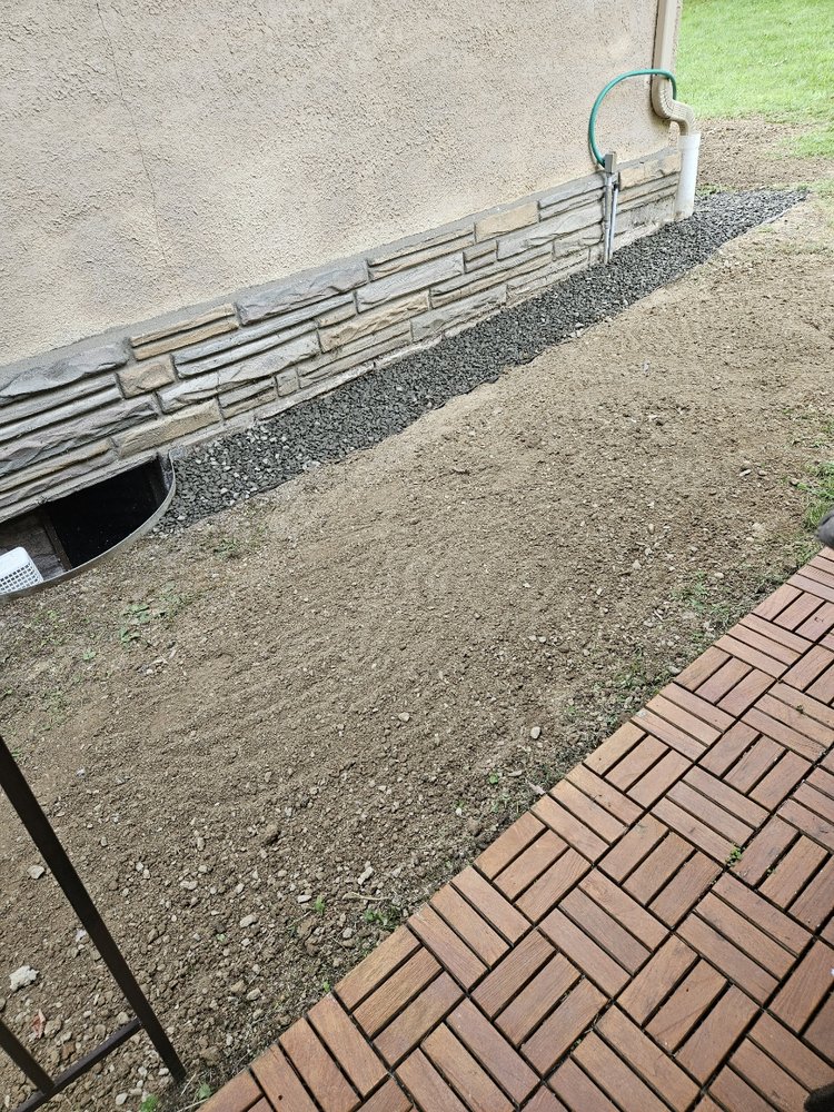 Gravel drainage and regraded soil beside a Highland Square home, basement waterproofing Akron