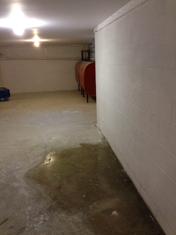 Water pooling on an Akron basement floor before basement waterproofing was installed